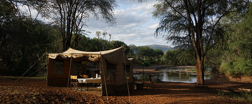 Mobile tented safari camp on the banks of a lagoon in African bush
