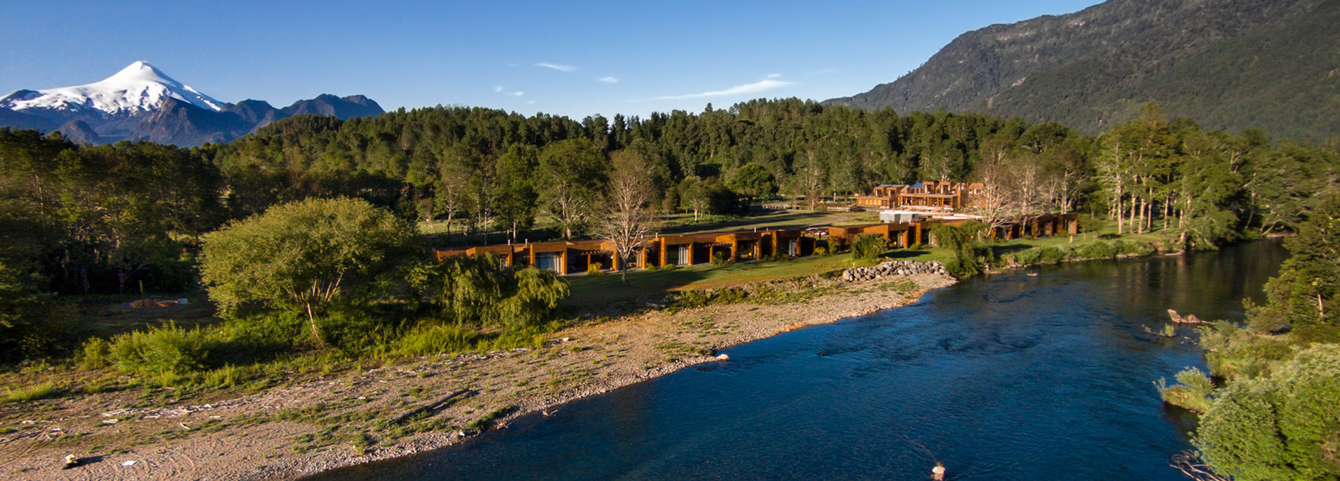 Hotel Vira Vira on the banks of the Liucura River in Chile, with snowcapped mountains in the background