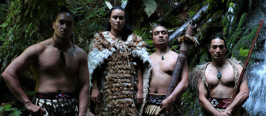 Proud Māori stand in front of a waterfall