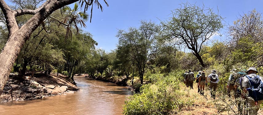 Tourists hiking alongside a river as part of the Great Walk of Africa
