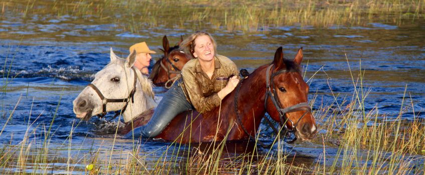 Julie McIntosh riding through the deep water of the Okavango Delta on a Classic Safari
