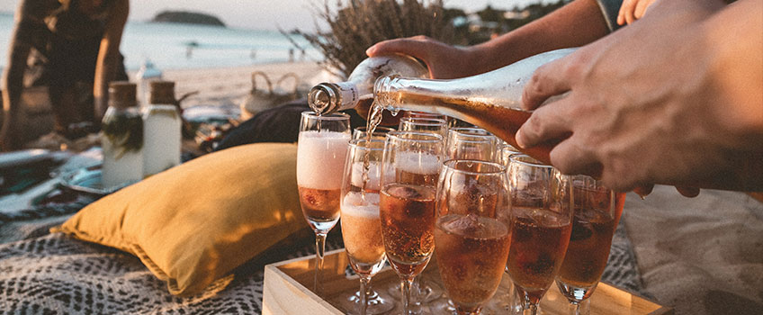 A beach picnic with champagne being poured