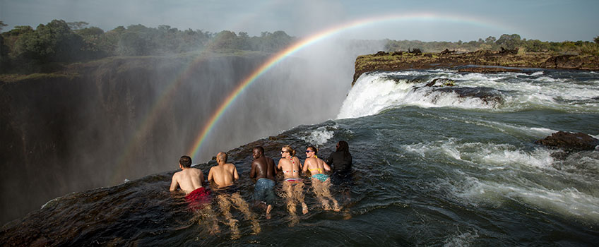 Swimming in Devil's Pool on the brink of Victoria Falls, with rainbows in the mist