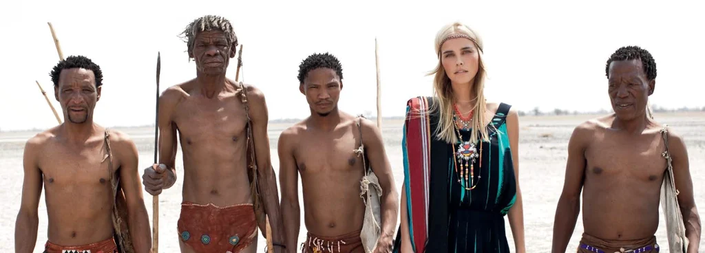 Isabel Lucas stands with San tribesmen on a Vogue Australia photo shoot on Botswana's Makgadikgadi Pans.