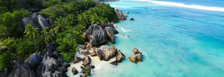 Aerial view of the Seychelles’ granite coastline with turquoise lagoons, palm forests and white-sand beaches.