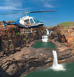 A helicopter flies over stunning waterfalls in Australia's Kimberley region 