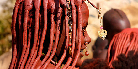 Close-up of a Himba woman with beaded hair coated in otjize paste.
