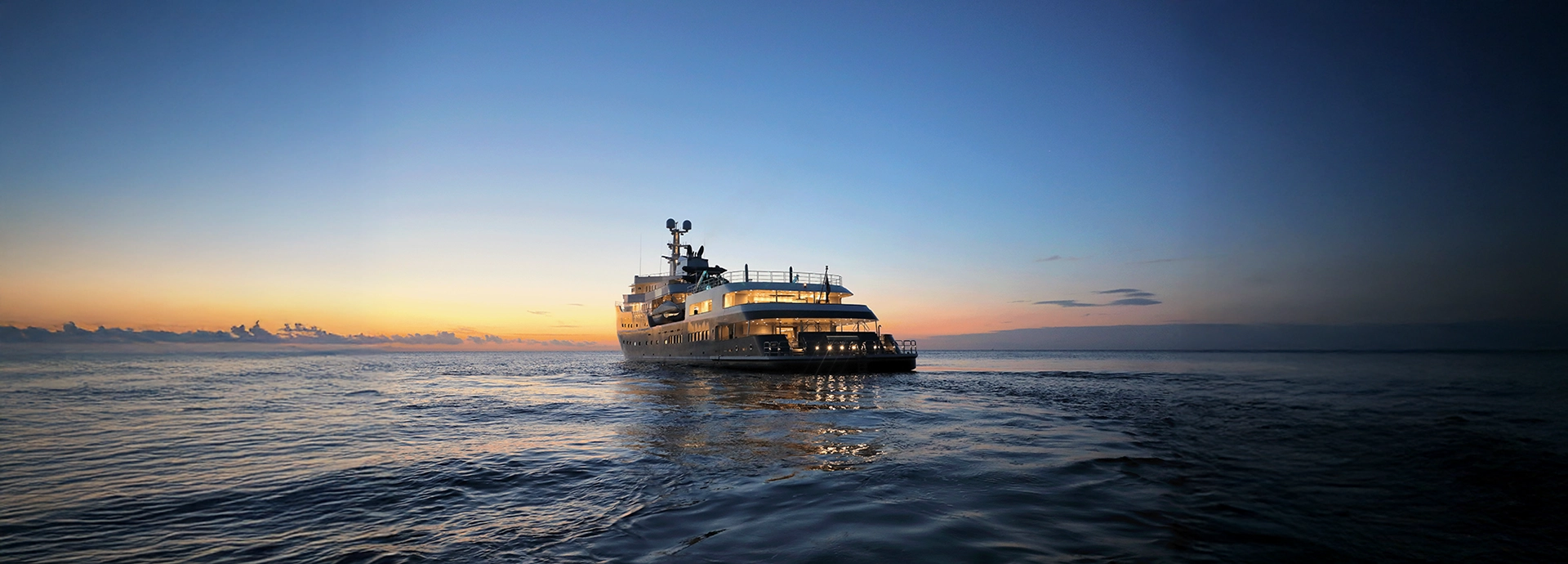 Aqua Lares illuminated at dusk as the sun sets over calm open seas.