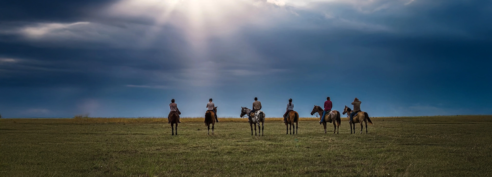 Riders pause beneath dramatic skies on the vast plains of the Simalaha Conservancy.