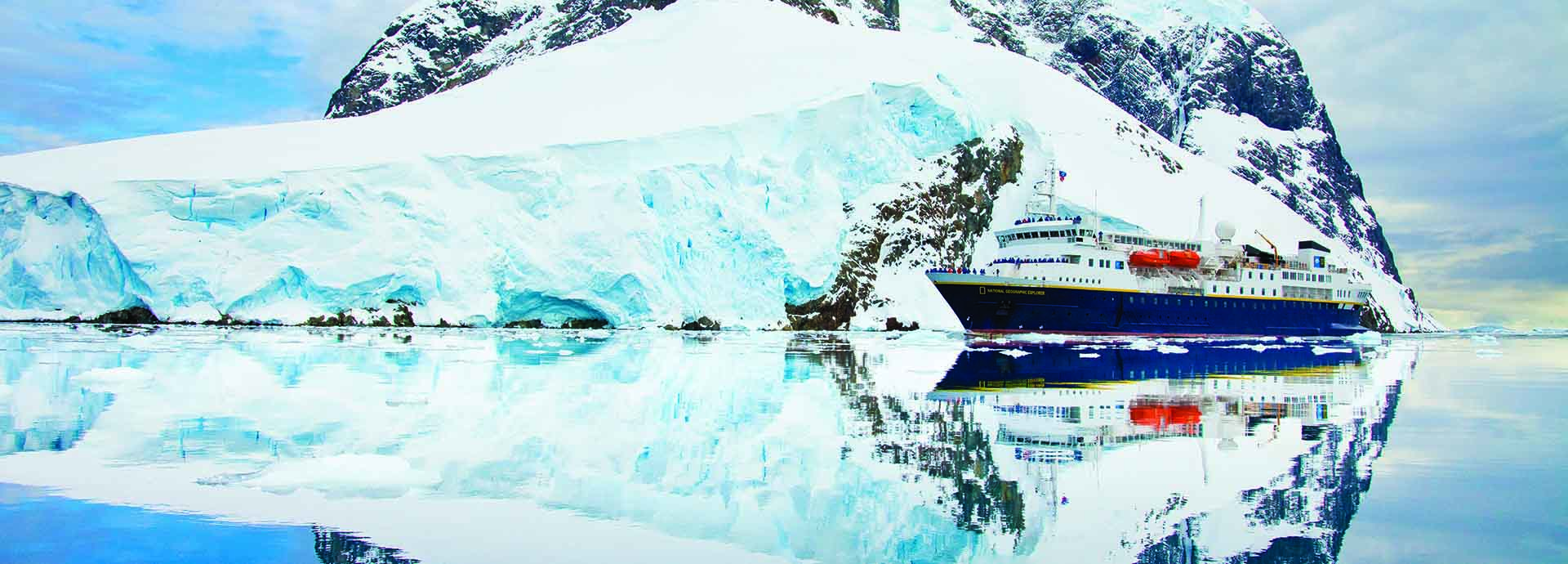 Large cruise ship drifts past mountains and glaciers in Antarctica