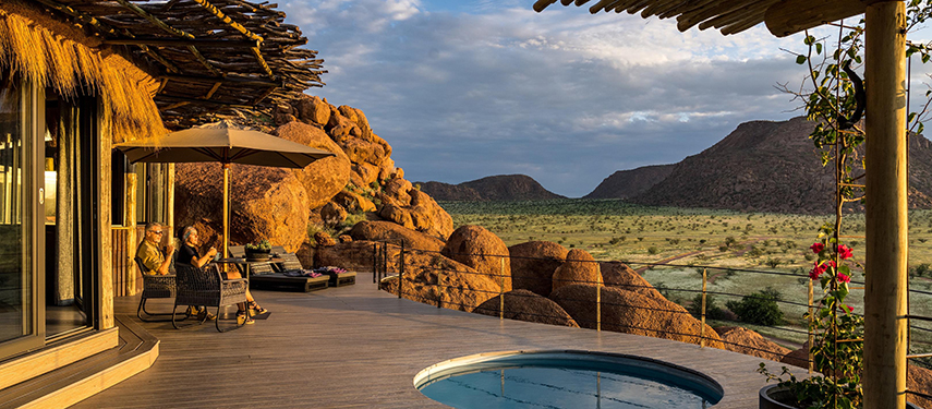 A couple enjoy sunset next to a plunge pool at a luxurious safari lodge in Namibia