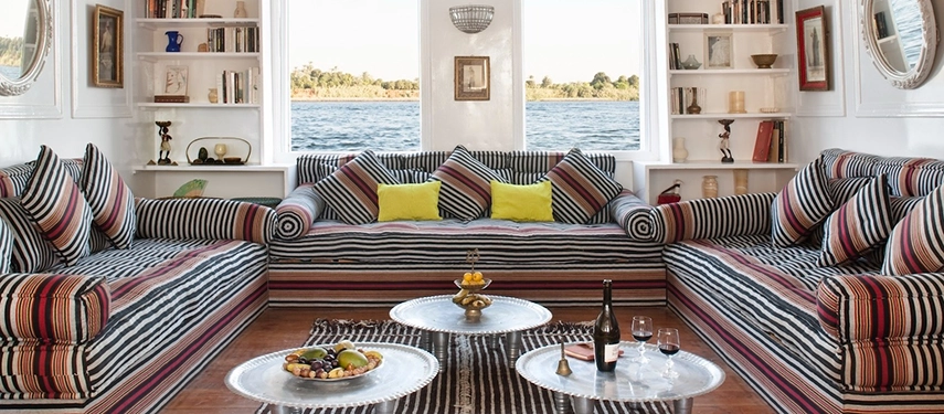 A vibrant salon dressed in striped textiles opens onto sweeping views of the Nile’s calm, shimmering waters.