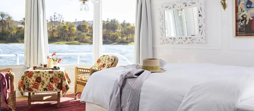 A light-filled cabin overlooks palm-dotted banks, with crisp linens and rattan chairs creating a gentle sense of calm.