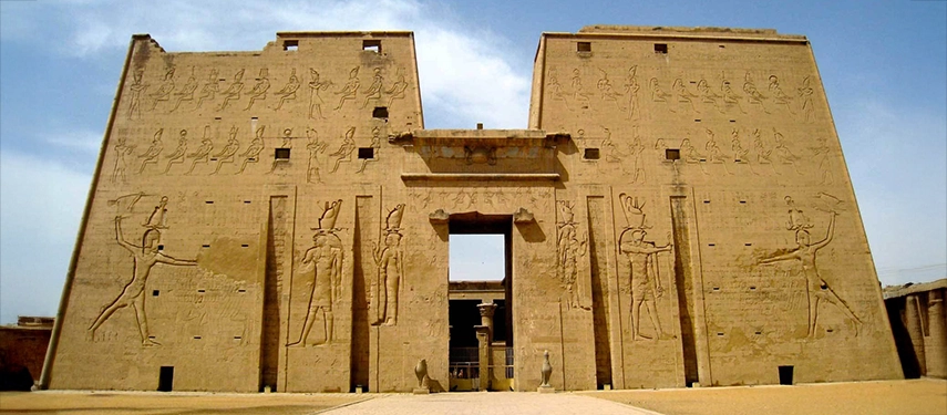 The monumental entrance of Edfu Temple rises against the sky, its towering walls alive with finely carved hieroglyphs.