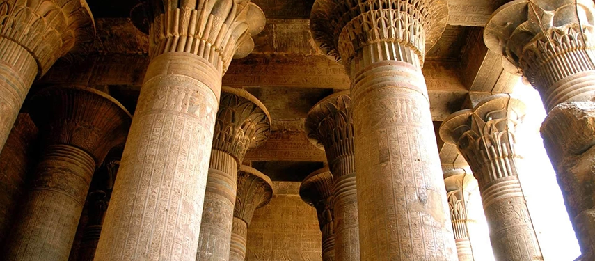 Sunlit columns of an ancient Egyptian temple rise skyward, their carved capitals glowing softly in the afternoon light.