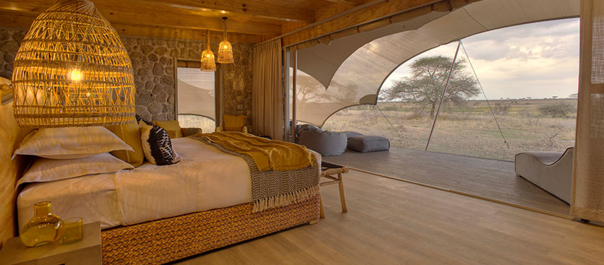 Luxurious yet cosy interior of a tented suite with views across the plains of the Serengeti