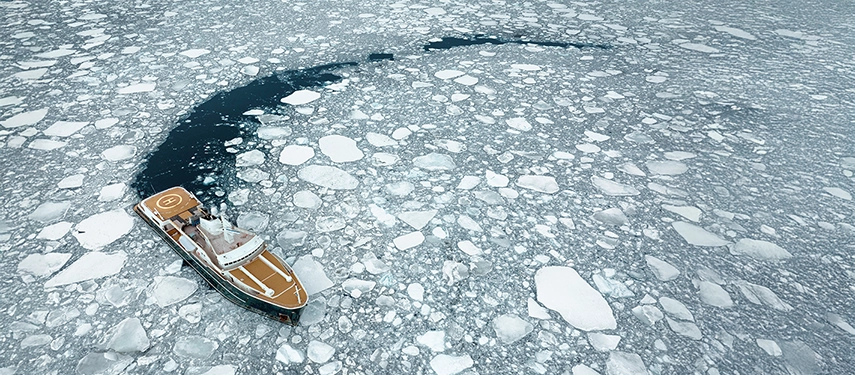 Aqua Lares carving a path through floating sea ice, its helipad visible on the upper deck.