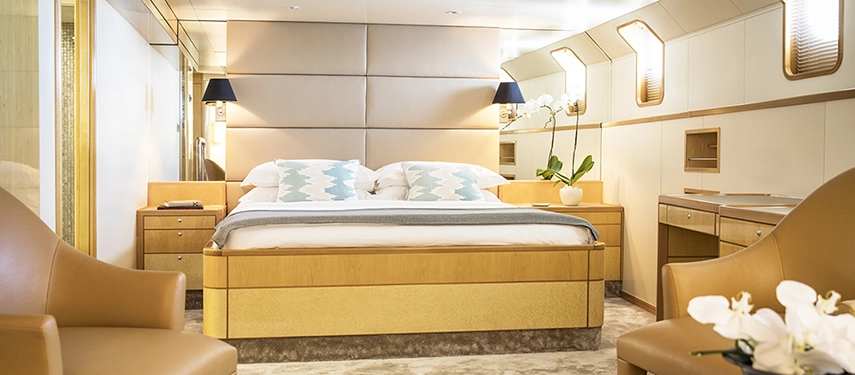 Elegant cabin with a plush king bed, soft lighting and natural tones, featuring polished wood finishes and serene ocean-inspired décor.