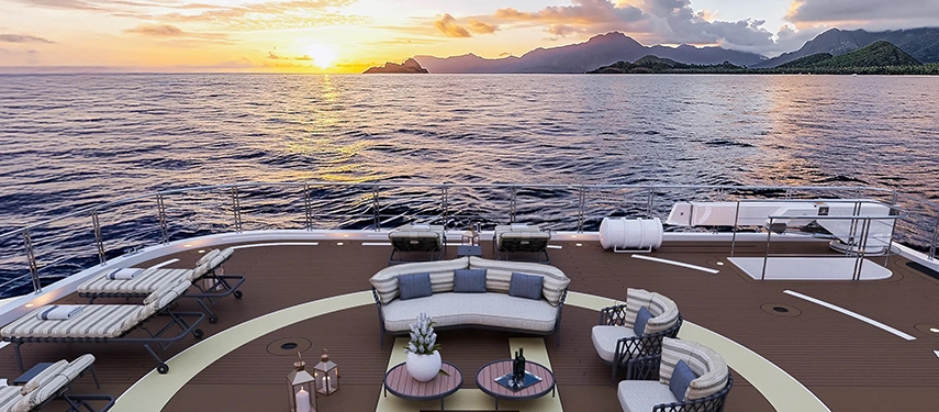 Elegant sun deck with circular lounge seating overlooking an ocean sunset.