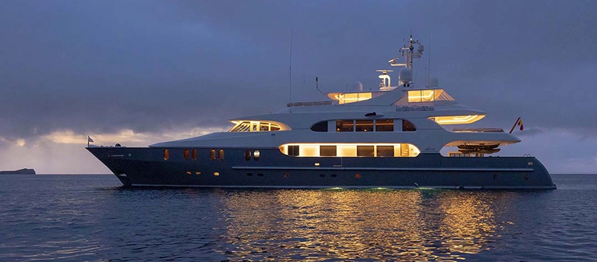 Aqua Mare glows softly at dusk, its elegant silhouette reflecting golden light across tranquil Galápagos waters.