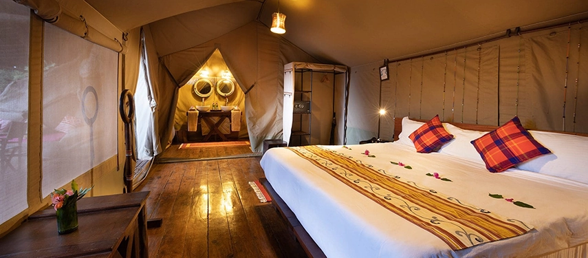 Spacious tented suite at Basecamp Masai Mara with a large bed, hardwood floors, and an en suite bathroom, offering comfort in the heart of the bush.