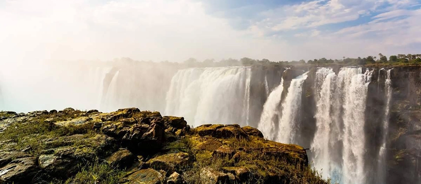 Spectacular view of Victoria Falls with mist rising and dramatic cliffs, a highlight of the Grand Zambezi Safari.