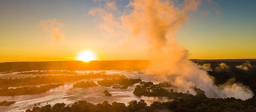 Golden sunrise mist rising over the Zambezi River at Victoria Falls