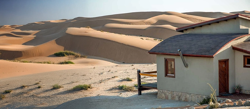 Isolated desert suite at Desert Breeze Lodge nestled among sweeping dunes, blending modern structure with natural surroundings.