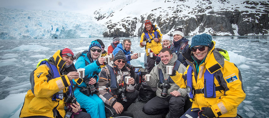 Tourists celebrate aboard a Zodiac surrounded by the ice floes of Antarctica