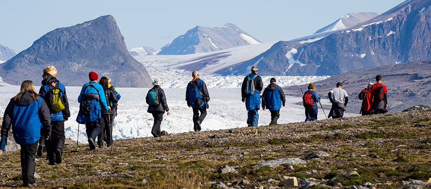 Tourists hike across the tundra of Norway with a glacier in the background