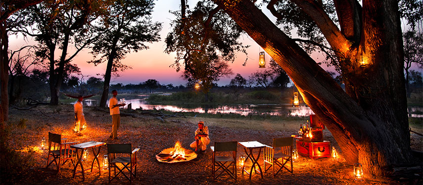 Share stories around the campfire at sunset by the river at Selinda Canoe Trail in Botswana