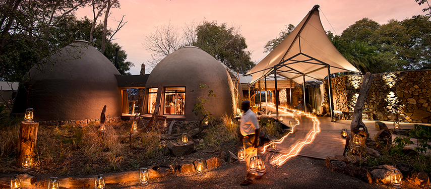 Entrance to a dome-shaped luxury suite at a safari lodge, with lanterns lighting the path at dusk.