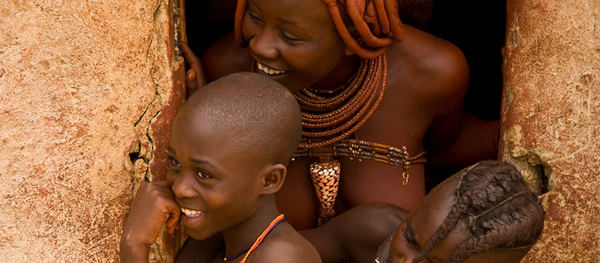 Himba mother and child stand in the door way of their home in Namibia