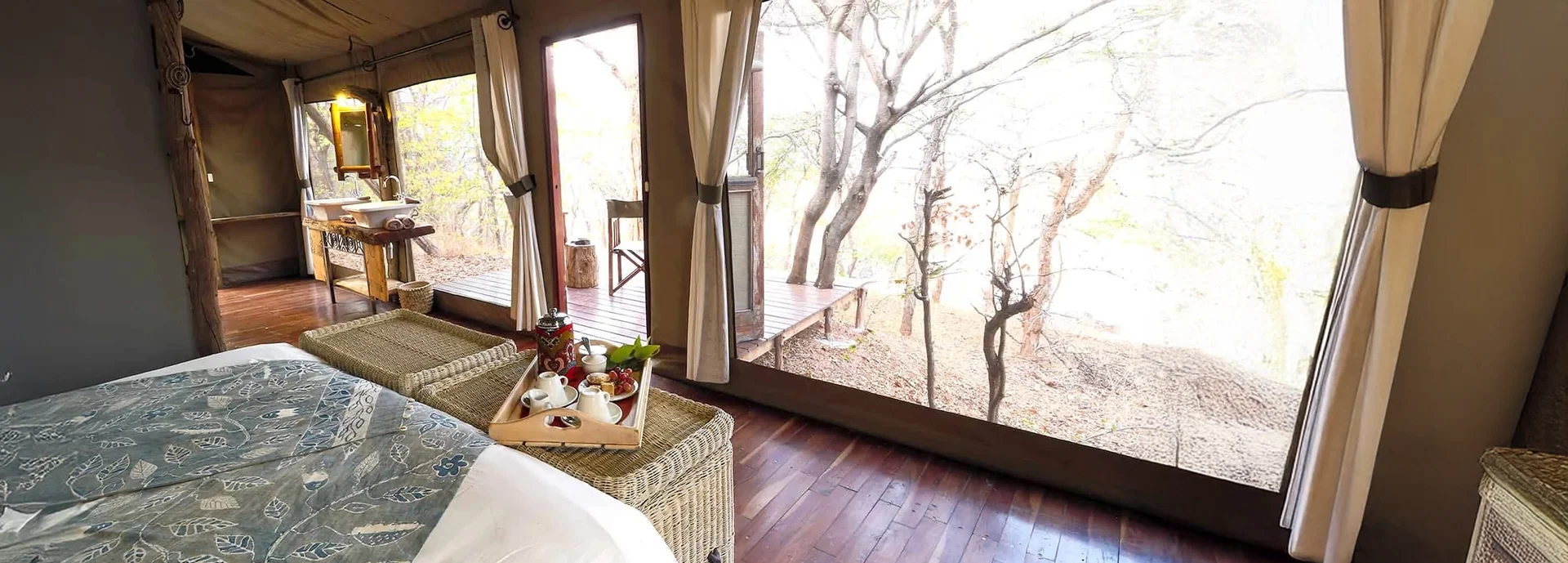 Tented suite interior at Changa Safari Camp featuring canvas walls, polished timber floors, and a private deck opening to the bush.